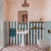 Bathroom featuring Bloom Rose Pink 20x20cm Moroccan-style patterned floor tiles, paired with teal and white striped wall tiles, textured pink walls, a pedestal sink and brass accents.