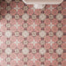 Close-up of Bloom Rose Pink 20x20cm Moroccan-style patterned bathroom floor tiles, featuring soft pink floral motifs, burgundy detailing and cream geometric accents, arranged in a repeating decorative design.