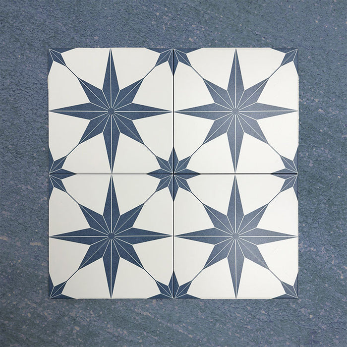 Pole Star Blue Moroccan-style 25x25cm patterned porcelain tiles arranged in a grouped layout, showcasing the repeating blue star motif on a soft white background.