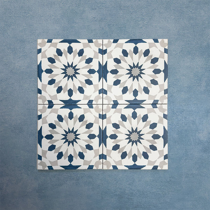 Group of Soukaina Blue A Moroccan-style 20cm x 20cm patterned porcelain tiles, showing a repeating geometric star design in deep blue, white and soft grey tones with a matt finish.