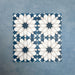 Group of Soukaina Blue D Moroccan-style 20cm x 20cm patterned porcelain tiles, showing a repeating central star motif in deep blue, white and soft neutral tones with a matt finish.