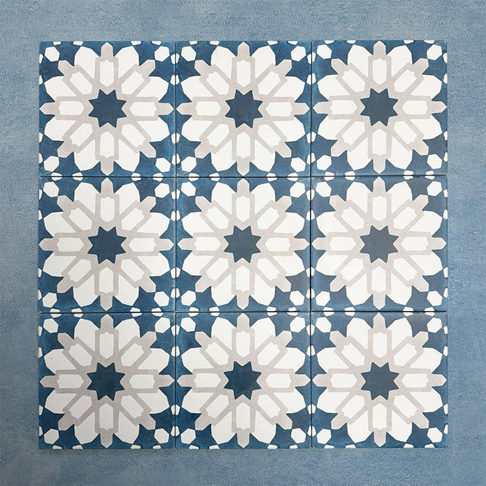 Group of Soukaina Blue D Moroccan-style 20cm x 20cm patterned porcelain tiles, showing a repeating central star motif in deep blue, white and soft neutral tones with a matt finish.