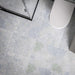 Bathroom floor featuring Boheme Blue Patterned 59.55cm x 59.55cm tiles, showcasing a soft patchwork design in blue, grey and subtle green tones, paired with a black framed shower enclosure and white bathroom fixtures.