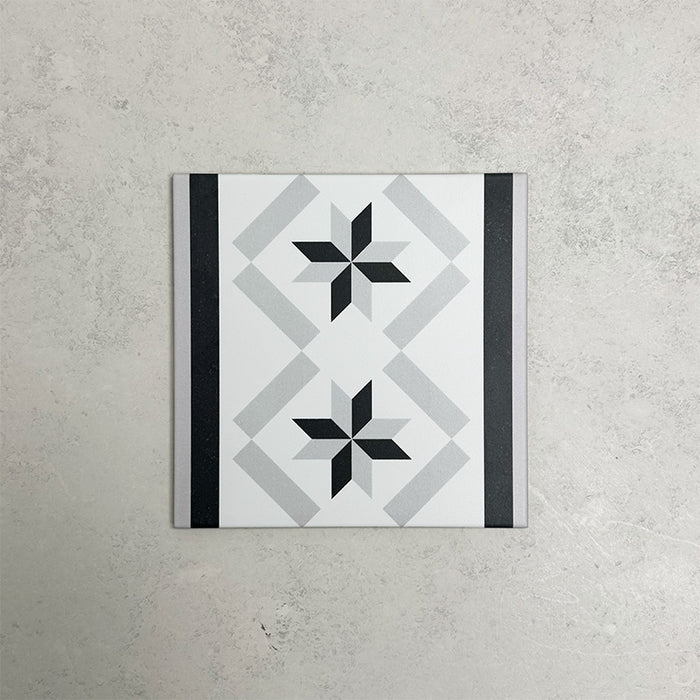 Georgetown Star Border Victorian-style 20x20cm patterned porcelain tile, featuring a monochrome star motif with contrasting black and grey border detailing.