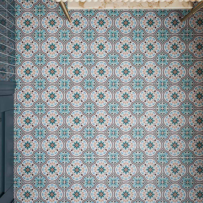 Close-up of Cabana Bayamo 20x20cm Moroccan-style patterned bathroom floor tiles, featuring intricate floral motifs in soft blue, turquoise and pink tones, arranged in a repeating geometric design.