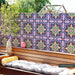 Outdoor seating area featuring Cabana Havana 20x20cm Moroccan-style patterned wall tiles, with vibrant navy blue, pink, green and yellow geometric floral motifs, creating a colourful backdrop behind a wooden bench with cushions.