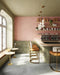 Café interior featuring Atlas Pink Mini Brick 5x15cm matt wall tiles, laid in a vertical brick format to emphasise height and create a soft, rhythmic backdrop. The muted pink tone introduces warmth without overwhelming the space, while the matt finish keeps the overall look refined and understated.