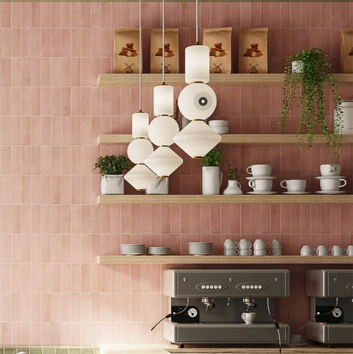 Café interior featuring Atlas Pink Mini Brick 5x15cm matt wall tiles, laid in a vertical brick format to emphasise height and create a soft, rhythmic backdrop. The muted pink tone introduces warmth without overwhelming the space, while the matt finish keeps the overall look refined and understated.