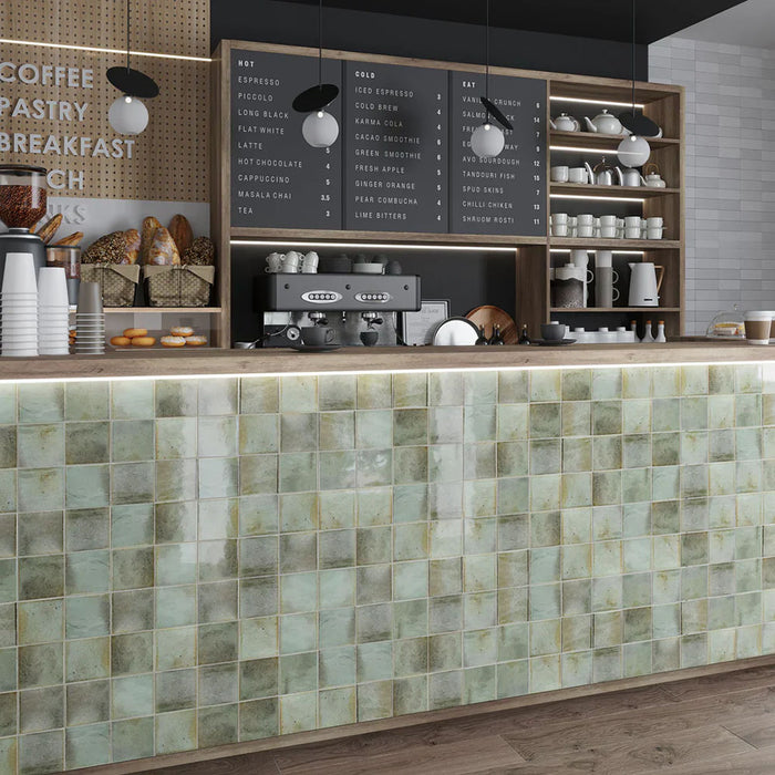 Café featuring Beijing Celadon Green Square 10x10cm Moroccan-style ceramic wall tiles, styled on a coffee bar with wooden shelving, modern lighting and neutral décor.