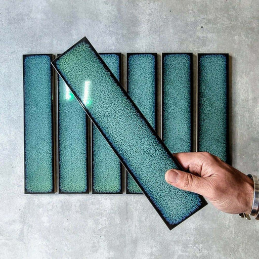 Marketing setting featuring Chemistry Green 6.5cm x 30cm rectangular ceramic wall tiles, showcasing a glossy crackle-effect glaze in rich green tones with a handcrafted effect, artisan finish.