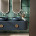 Chemistry Green 6.5cm x 30cm wall tiles, featuring rich green tones and dark edging behind a statement double vanity with deep blue basins, fluted cabinetry and brass details.