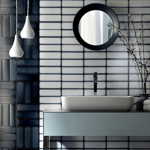 Bathroom setting featuring Chemistry White 6.5cm x 30cm rectangular ceramic wall tiles, installed in a stacked layout with a glossy crackle-effect white glaze and dark grout for a contemporary, artisan finish.