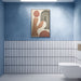 Chemistry White 6.5cm x 30cm wall tiles installed vertically across the lower half of a modern bathroom wall, featuring a crisp white finish with contrasting dark blue edges, paired with soft blue walls and a white wall-mounted toilet.