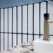 Close-up of Chemistry White 6.5cm x 30cm wall tiles installed vertically, showcasing the crisp white surface and contrasting dark blue edges, styled with a terrazzo effect vanity top and brushed brass tap.