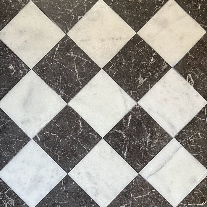 Flat lay of Fitzrovia White 15.2x15.2cm honed natural marble tiles paired with dark marble in a classic chequerboard pattern, showcasing soft white tones, deep contrast, natural veining, and a smooth, refined finish.