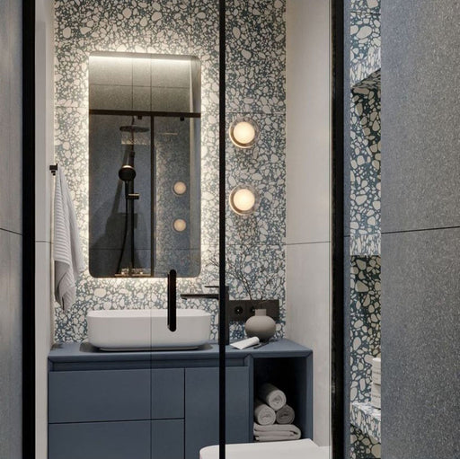 Modern bathroom featuring Chunks Pop Blue 60cm x 120cm terrazzo effect porcelain feature wall tiles, paired with large-format grey wall tiles, a blue floating vanity, black brassware and illuminated mirror.