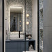 Modern bathroom featuring Chunks Pop Blue 60cm x 120cm terrazzo effect porcelain feature wall tiles, paired with large-format grey wall tiles, a blue floating vanity, black brassware and illuminated mirror.