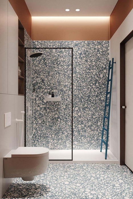 Contemporary bathroom featuring Chunks POP Terrazzo Blue 60 × 60cm terrazzo-effect porcelain wall and floor tiles, paired with black shower framing, warm terracotta walls, and minimalist white sanitaryware for a bold modern finish.