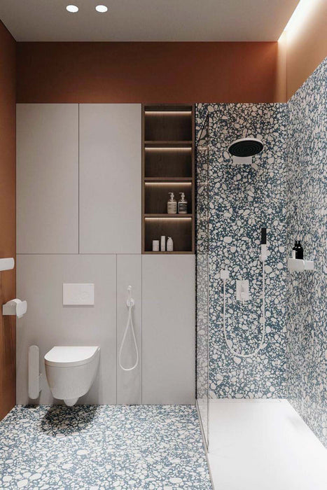 Contemporary bathroom featuring Chunks POP Terrazzo Blue 60 × 60cm terrazzo-effect porcelain wall and floor tiles, paired with black shower framing, warm terracotta walls, and minimalist white sanitaryware for a bold modern finish.