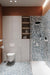 Contemporary bathroom featuring Chunks POP Terrazzo Blue 60 × 60cm terrazzo-effect porcelain wall and floor tiles, paired with black shower framing, warm terracotta walls, and minimalist white sanitaryware for a bold modern finish.