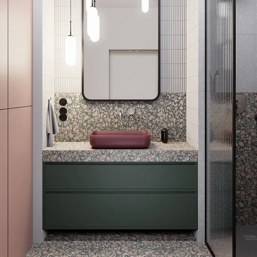 Modern bathroom featuring Chunks POP Terrazzo Green 60 × 120cm terrazzo-effect porcelain wall and floor tiles, paired with deep green cabinetry, a burgundy basin, ribbed glass shower screen, and soft contemporary lighting.
