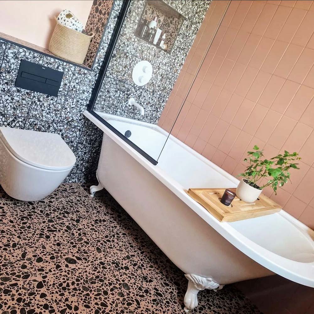 Bathroom featuring Chunks POP Terrazzo Pink 60 × 60cm terrazzo-effect porcelain floor tiles, paired with blush pink wall tiles, monochrome terrazzo shower walls, and a classic freestanding bath for a playful contemporary look.