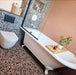 Bathroom featuring Chunks POP Terrazzo Pink 60 × 60cm terrazzo-effect porcelain floor tiles, paired with blush pink wall tiles, monochrome terrazzo shower walls, and a classic freestanding bath for a playful contemporary look.