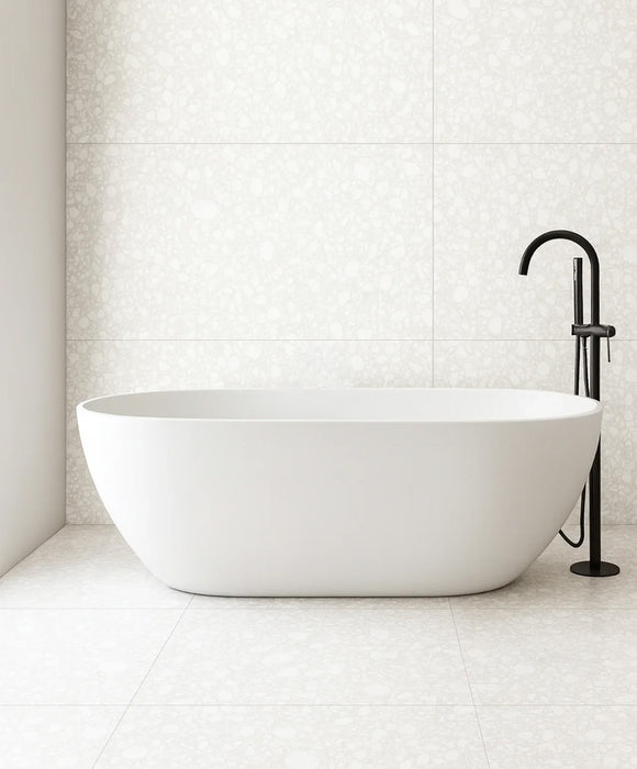 Minimalist bathroom featuring Chunks Pop White 60cm x 120cm terrazzo effect porcelain wall and floor tiles, paired with a freestanding bath and black brassware for a bright, contemporary spa-inspired interior.