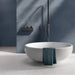 Minimalist bathroom featuring Chunks POP Terrazzo White 60 × 60cm terrazzo-effect porcelain floor tiles, paired with deep blue wall tiles, a sculptural freestanding bath, and soft natural lighting for a calm contemporary feel.