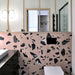 Modern bathroom featuring Chunks ROCK Terrazzo Pink 60 × 60cm terrazzo-effect porcelain wall tiles, showcasing oversized black marble-inspired fragments, paired with minimalist black fittings and light wood framed mirrors.