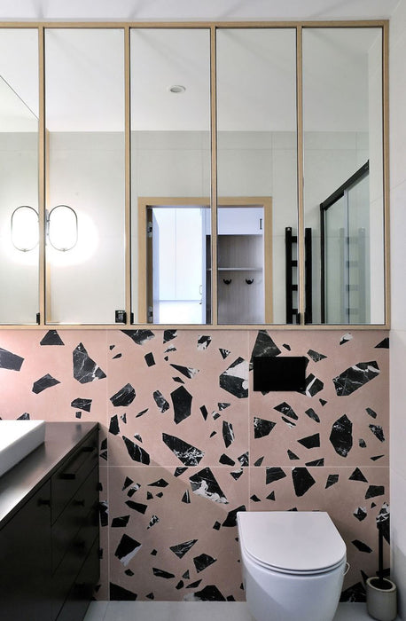 Modern bathroom featuring Chunks ROCK Terrazzo Pink 60 × 60cm terrazzo-effect porcelain wall tiles, showcasing oversized black marble-inspired fragments, paired with minimalist black fittings and light wood framed mirrors.