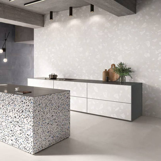 Contemporary kitchen featuring Chunks ROCK Terrazzo White 60 × 120cm terrazzo-effect porcelain wall tiles, paired with minimalist grey cabinetry, concrete ceilings, and a statement terrazzo kitchen island for a sleek modern interior.