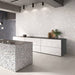 Contemporary kitchen featuring Chunks ROCK Terrazzo White 60 × 120cm terrazzo-effect porcelain wall tiles, paired with minimalist grey cabinetry, concrete ceilings, and a statement terrazzo kitchen island for a sleek modern interior.