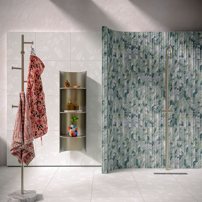 Bathroom featuring Chunks Rock Terrazzo White 60x60cm terrazzo-effect porcelain wall and floor tiles, styled with a curved shower wall, green patterned feature tiles, brushed brass fixtures and soft contemporary décor.