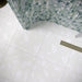 Bathroom featuring Chunks Rock Terrazzo White 60x60cm terrazzo-effect porcelain wall and floor tiles, styled with a curved shower wall, green patterned feature tiles, brushed brass fixtures and soft contemporary décor.