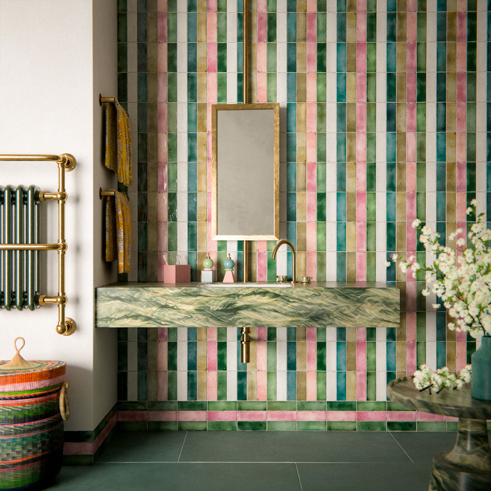 Bathroom setting featuring Fusion collection gloss brick tiles in a vertical striped layout, blending soft greens, pinks and neutrals, paired with a marble vanity and brass fittings for a vibrant, design-led finish.
