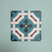 Four Europa Cologne 20x20cm Victorian Moroccan style tiles arranged together to showcase the repeating geometric pattern in teal, brown, cream and dark blue tones, displayed against a textured aqua background.