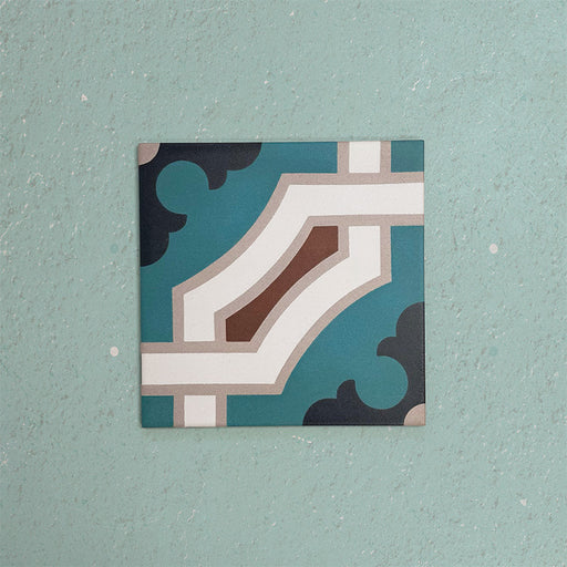 Single Europa Cologne 20x20cm Victorian Moroccan style tile displayed against a textured aqua background, featuring a decorative geometric corner pattern in teal, brown, cream and dark blue tones in a close-up product setting.