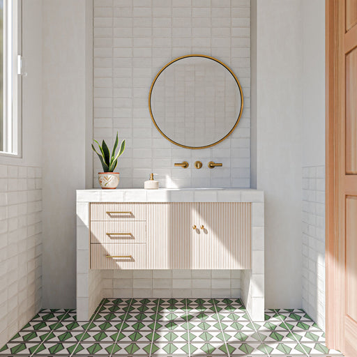 Bathroom featuring Cotswolds Rustic White Blanca 7.5cm x 15cm rustic gloss wall tiles, showcasing soft white tones and subtle surface variation, paired with green geometric floor tiles, a fluted vanity and brass details.