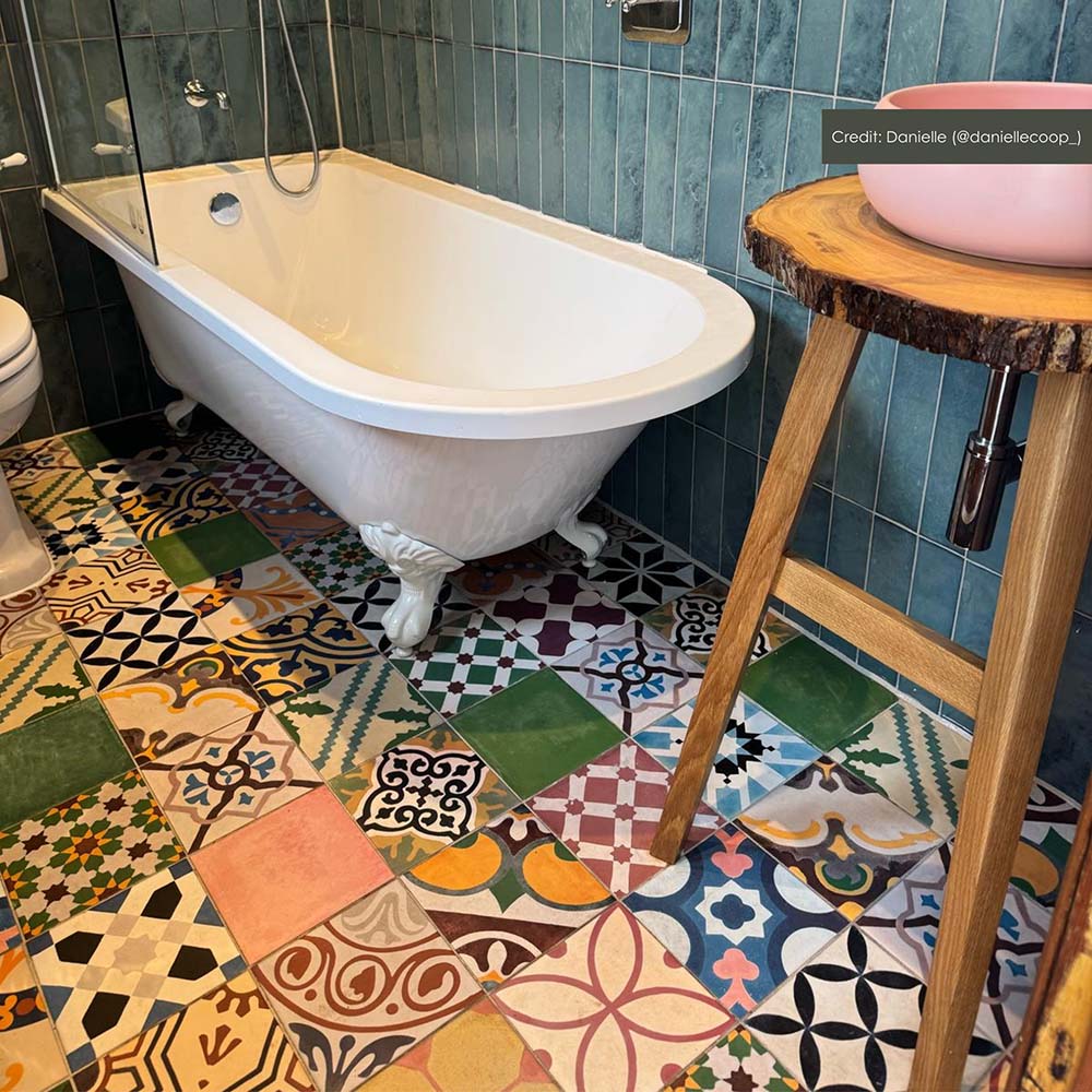 Bathroom setting featuring Fihrdos Patchwork Moroccan-style 20x20cm patterned porcelain floor tiles, combining colourful geometric designs beneath a freestanding bath and teal wall tiles.