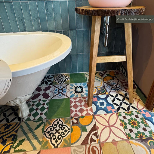 Bathroom setting featuring Fihrdos Patchwork Moroccan-style 20x20cm patterned porcelain floor tiles, combining colourful geometric designs beneath a freestanding bath and teal wall tiles.