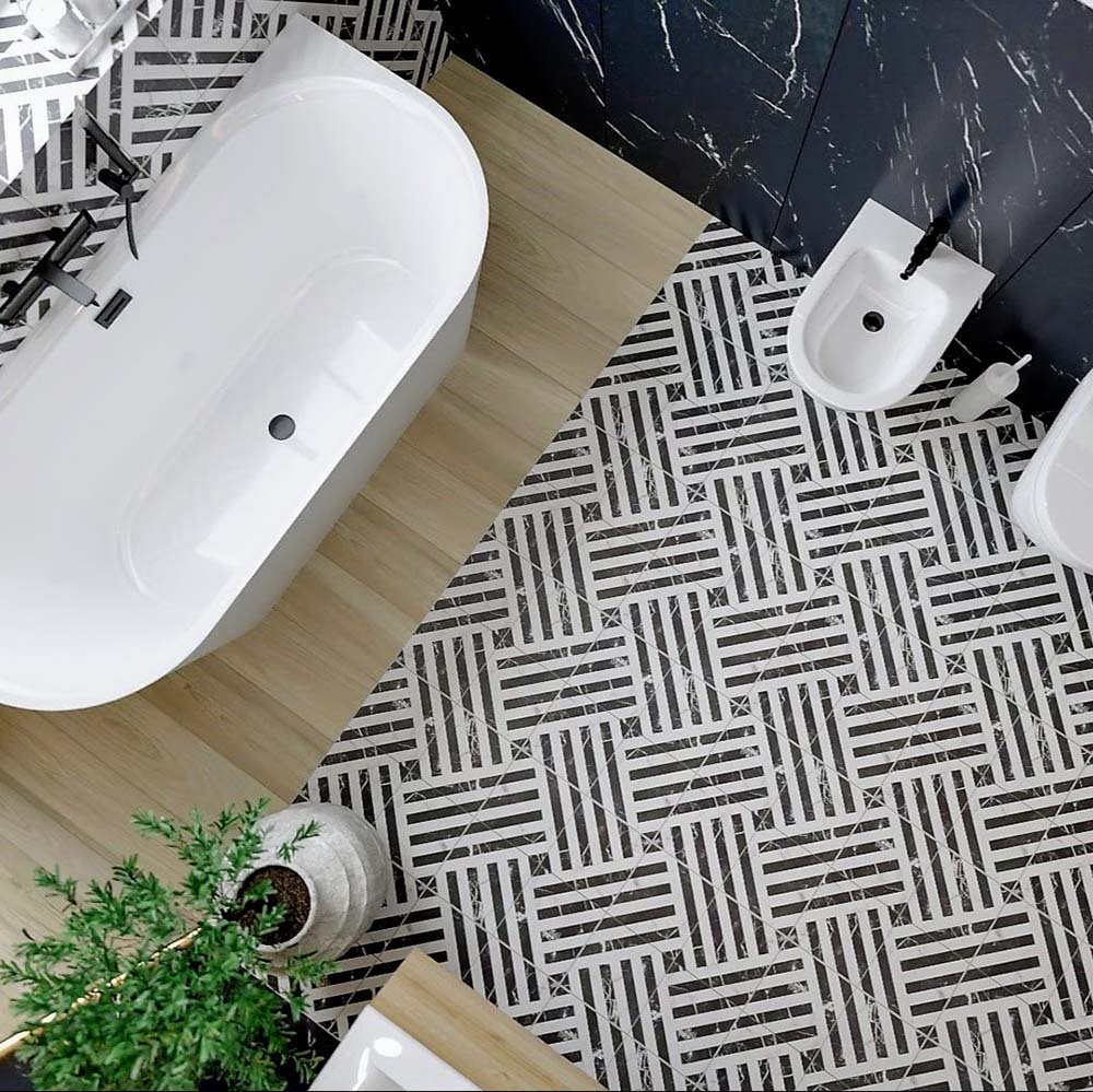 Top-down bathroom view featuring Decaprio Black & White marble effect patterned porcelain tiles 44 × 44cm, laid across the floor to create a bold, interlocking geometric design. The contrasting black and white tones add rhythm and structure, balanced with a freestanding bath, wood-effect flooring transition, and matte black fittings for a clean, contemporary finish.