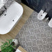 Top-down bathroom view featuring Decaprio Black & White marble effect patterned porcelain tiles 44 × 44cm, laid across the floor to create a bold, interlocking geometric design. The contrasting black and white tones add rhythm and structure, balanced with a freestanding bath, wood-effect flooring transition, and matte black fittings for a clean, contemporary finish.