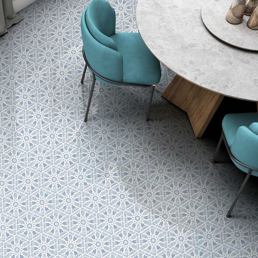 Maroush Mareshan Azure Blue 18.7x21.6cm Moroccan hexagonal tiles with intricate white geometric patterns, styled in a modern dining room with teal chairs and a round stone table for a fresh Mediterranean feel.