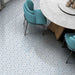 Maroush Mareshan Azure Blue 18.7x21.6cm Moroccan hexagonal tiles with intricate white geometric patterns, styled in a modern dining room with teal chairs and a round stone table for a fresh Mediterranean feel.
