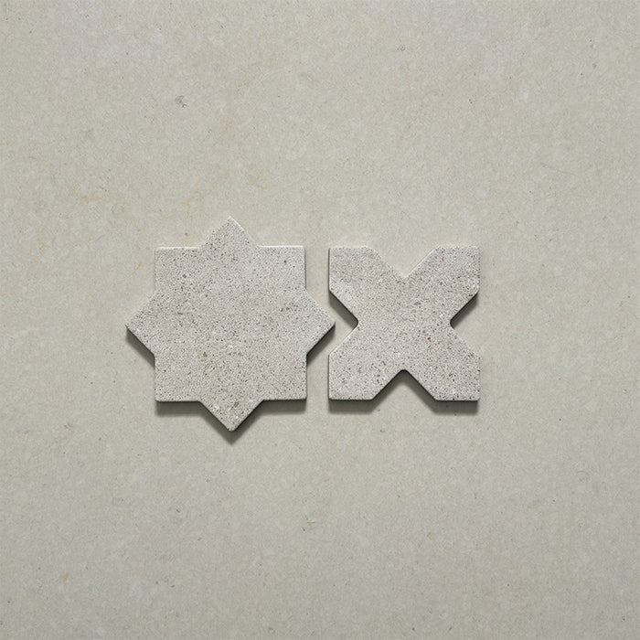 Close-up of Dohar Avorio Rocks Star & Cross porcelain wall and floor tiles, showcasing the coordinating geometric shapes, soft ivory colour, fine speckled detail and textured matt finish.