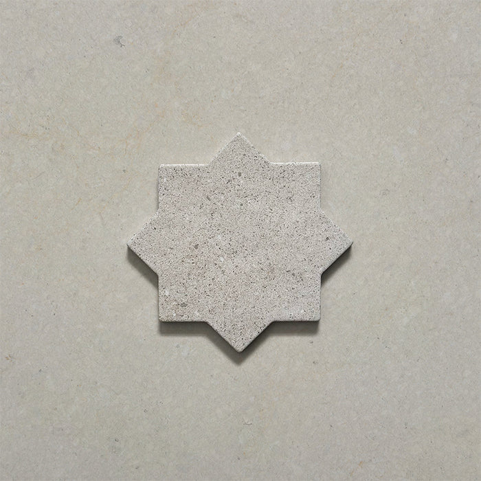 Close-up of a single Dohar Avorio Rocks Star porcelain wall and floor tile, showcasing its geometric eight-point star shape, soft ivory tone, fine speckled detail and textured matt finish.