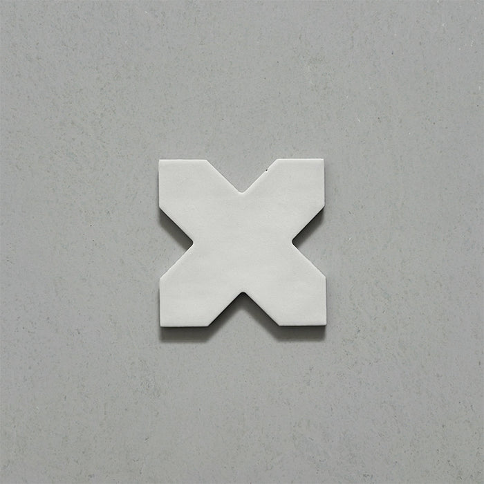 Close-up of a single Dohar Bone Cross Moroccan style porcelain wall and floor tile, showcasing the distinctive cross shape, soft off-white tone and subtle matt finish.