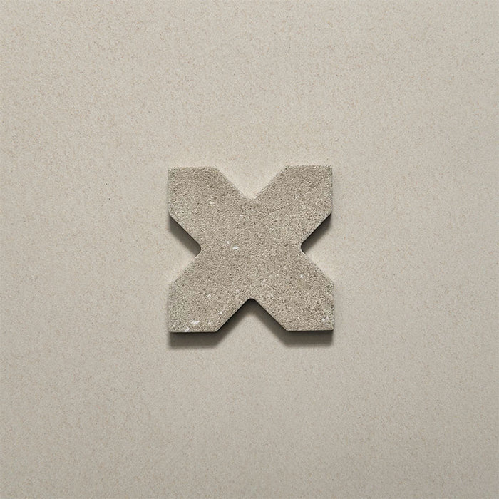 Close-up of a single Dohar Sands Cross porcelain wall and floor tile, showcasing the distinctive cross shape, warm sandy beige tone, speckled surface detail and subtle matt finish.