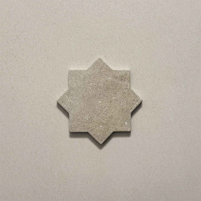 Close-up of a single Dohar Sands Star porcelain wall and floor tile, showcasing the distinctive eight-point star shape, warm sandy beige tone, speckled surface detail and subtle matt finish.